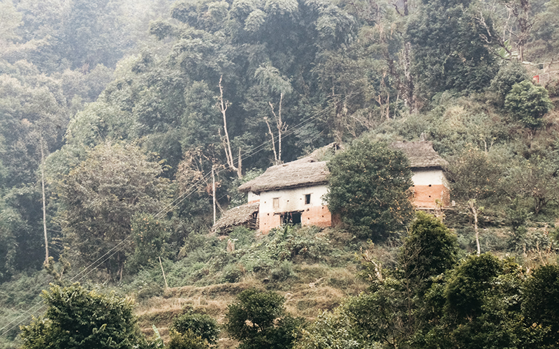 A large mud and thatch house, which is home for the reading camp, sits on a hillside in Nepal.
