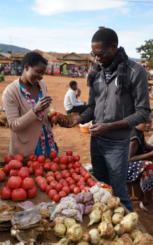 Un homme achète de la nourriture à une femme sur un marché de Beni, en République démocratique du Congo.