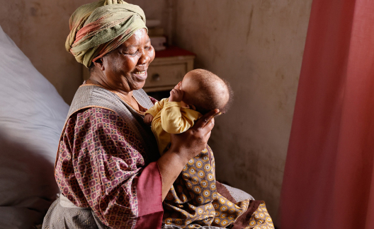 A woman is smiling while gently holding a baby.