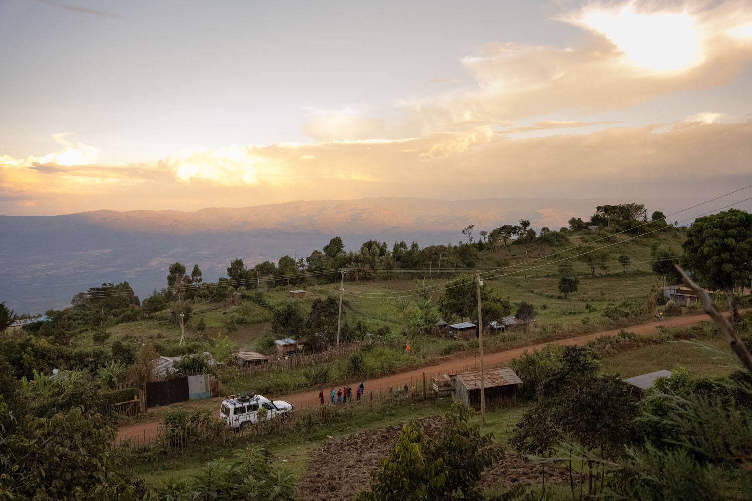 The sun rises over Kenya’s Rift Valley, with a few Kenyans gathered on the road below. 