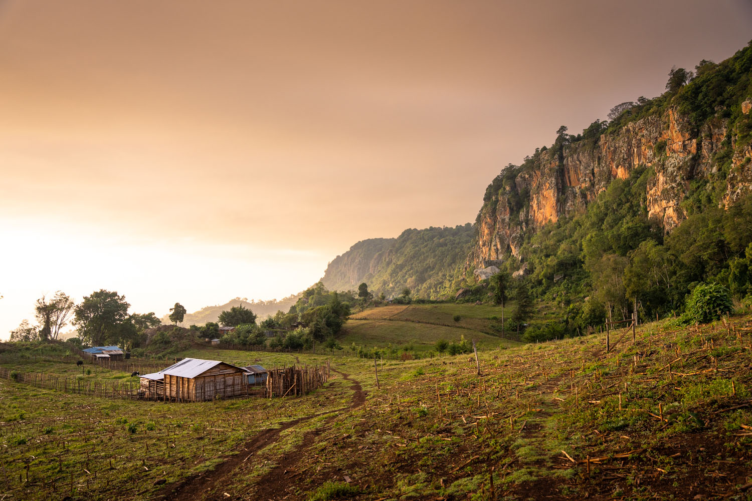 A small house sits at the bottom of some cliffs in Rift Valley, Kenya. 