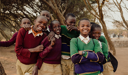 A group of students stand together outdoors, laughing and smiling.