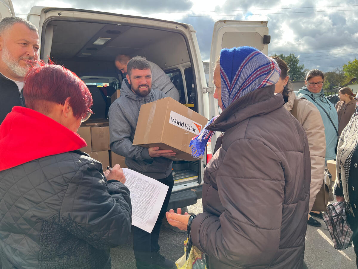 People gather around a van, unloading boxes.