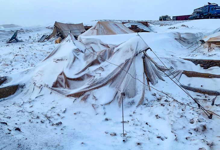 A clutch of rudimentary tents covered in snow. There’s no one in sight.