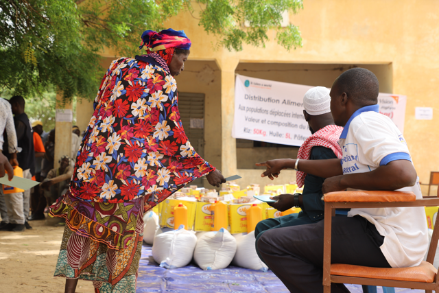 Volunteers distributing food items and interacting with families in Mali.