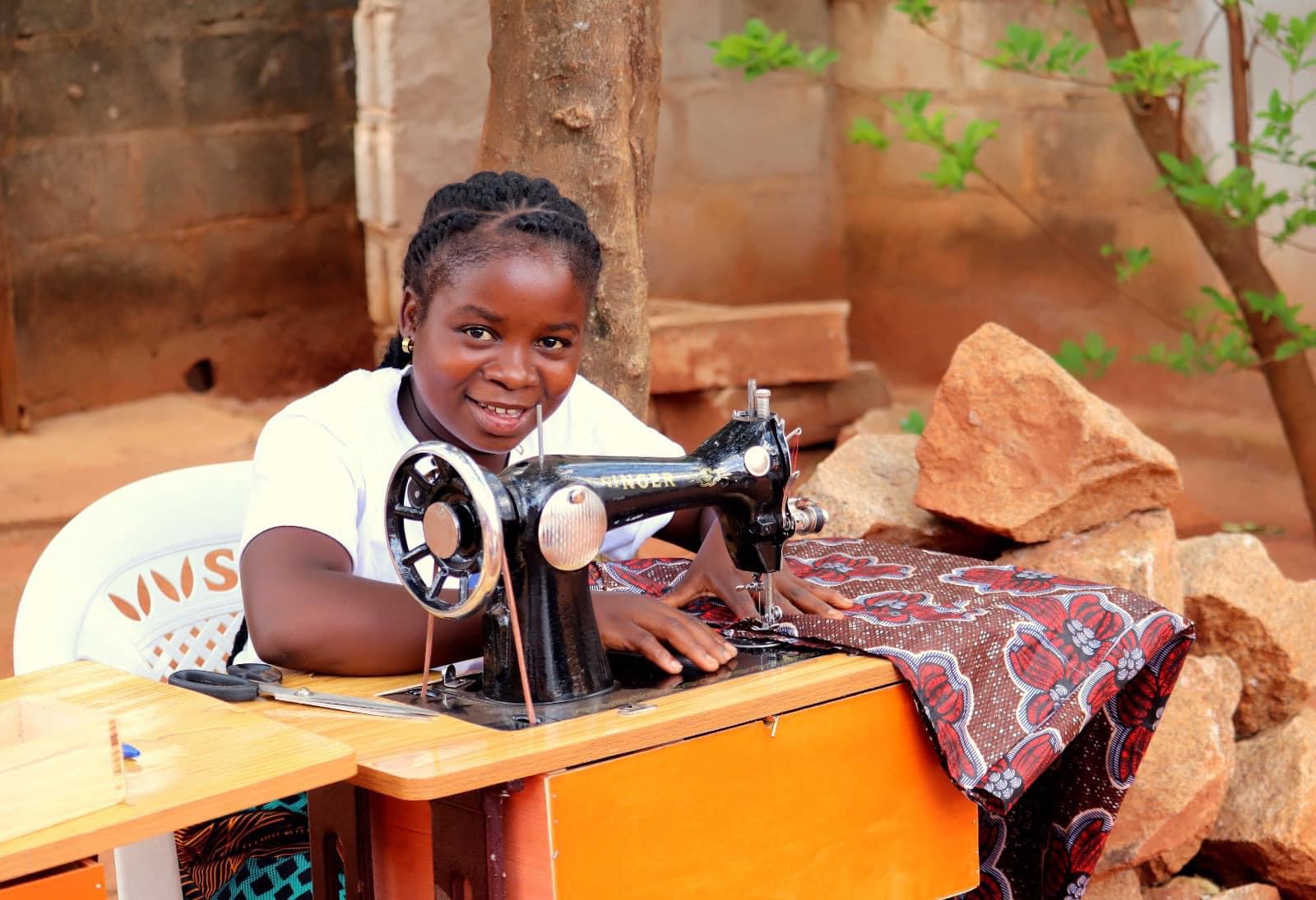 A girl smiles while sewing.