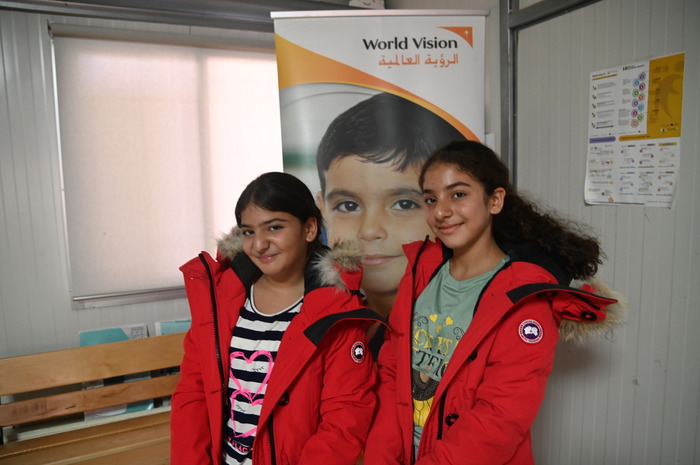 In Lebanon, two adolescent girls smile while trying on their bright-red Canada Goose parkas.