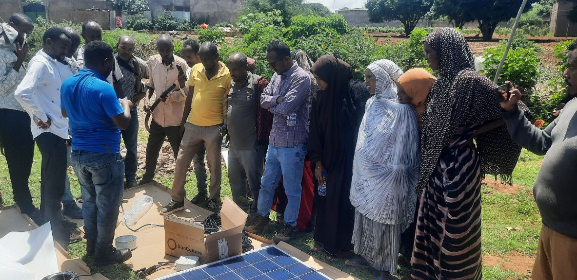 A technician shows community members how to use a solar water pump.