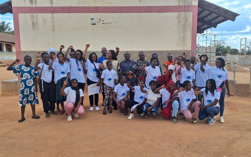 A group of adolescent advocates trained through Every Girl Can pose in a group and wave.