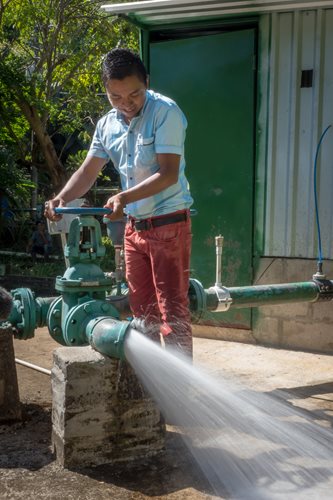 A young man from El Salvador operates a water pump system.