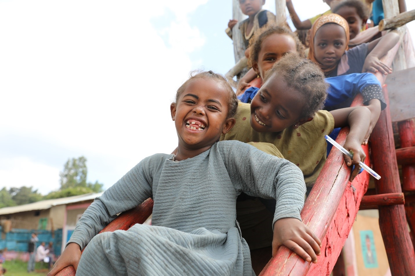 A group of children smile on a slide.
