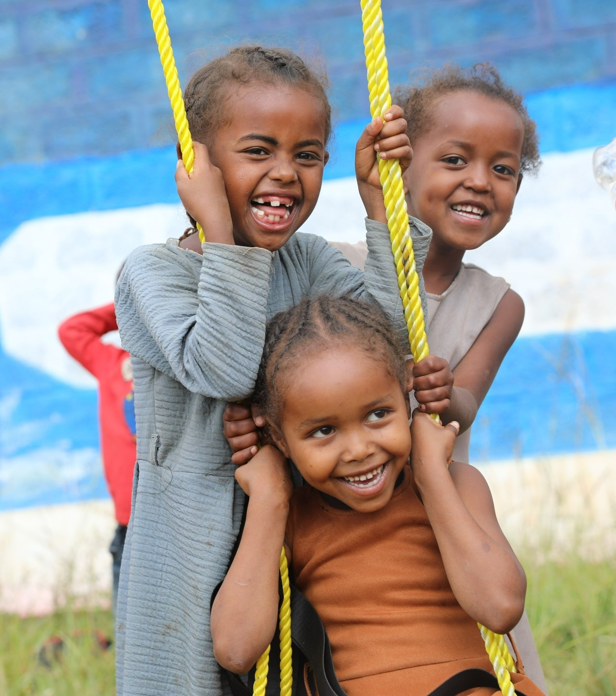 A group of children smile on a swing.