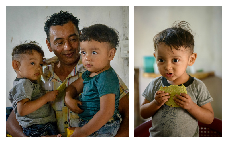 A man holds his two sons on the left, on the right a little boy eats a green tortilla.