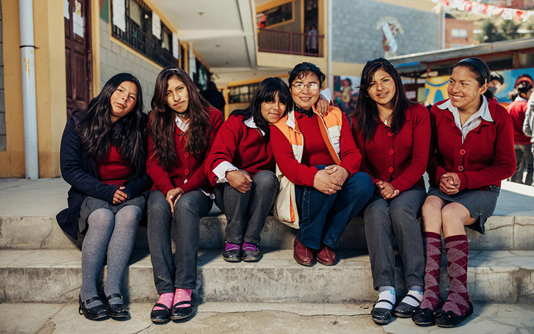 A woman who works for World Vision sits with a group of five high school girls.